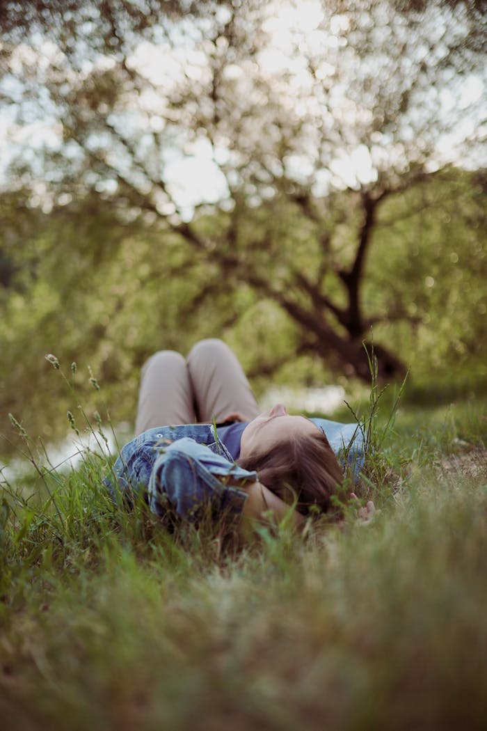 gallery-1 A person enjoying peaceful relaxation lying in a summer meadow surrounded by lush greenery.