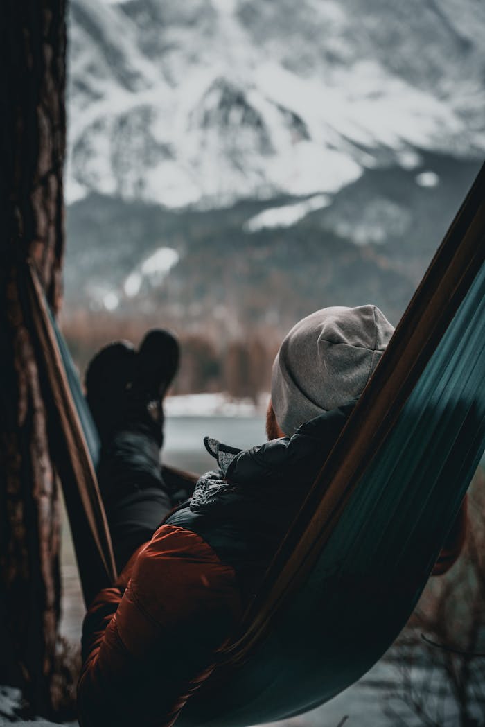 gallery-3 Man relaxing in a hammock during winter in Grainau, Bavaria, with snowy mountains in the background.