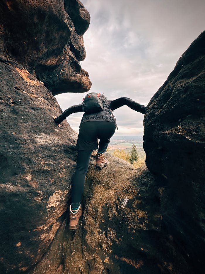 services-01 A hiker climbing through narrow rock formations in Oybin, Germany. An outdoor adventure scene.